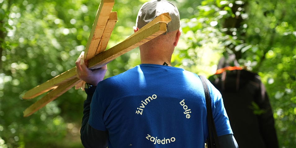 Back view of a man in workwear holding three poles.
