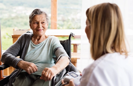 An elderly woman in a wheelchair and a younger woman smiling.
