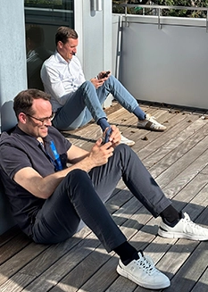 René Knapp and Wolf Gerlach sitting on a sunny balcony during a strategy retreat.
