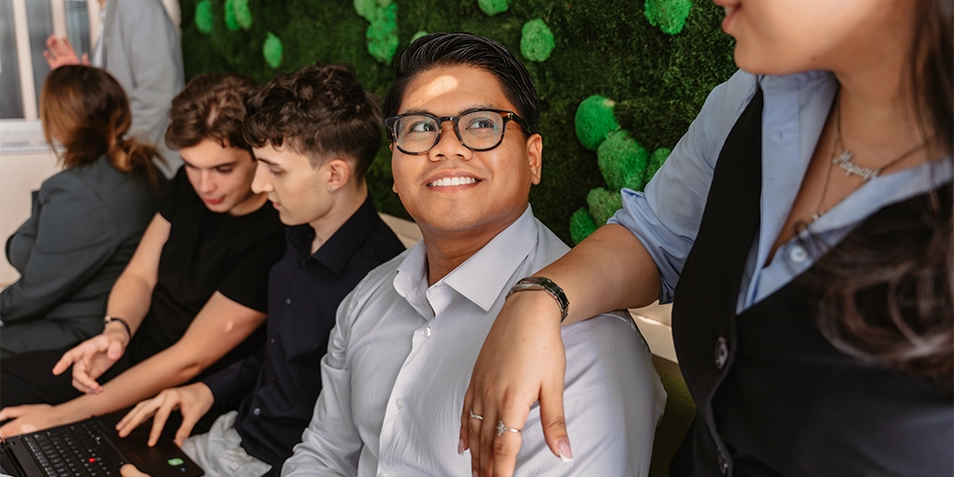 Five young people talking in front of laptops
